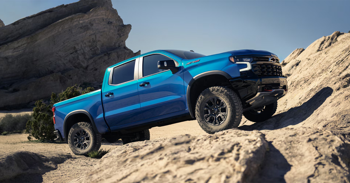 A blue 2026 Chevrolet Silverado 1500 parked in a rocky off-road desert terrain.